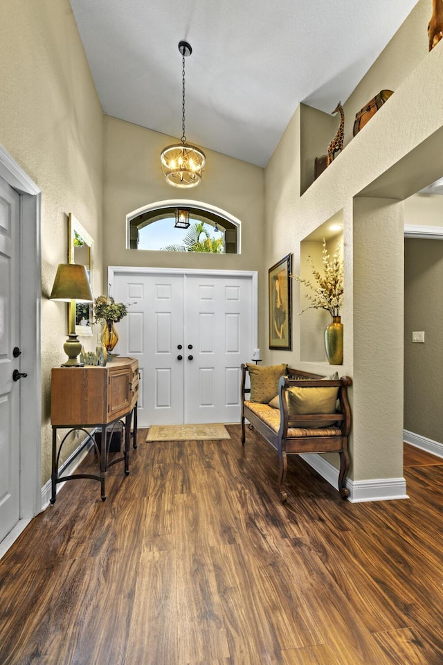 foyer with a towering ceiling, wood finished floors, and a chandelier