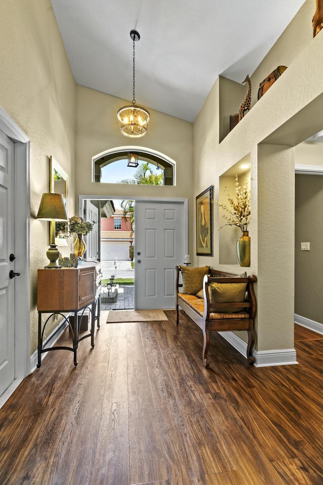 entryway featuring an inviting chandelier, a high ceiling, a textured wall, and wood finished floors