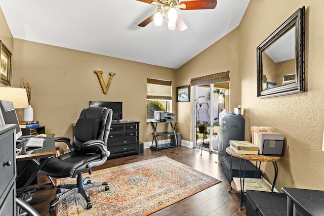 office space featuring a ceiling fan, vaulted ceiling, baseboards, a textured wall, and dark wood-type flooring