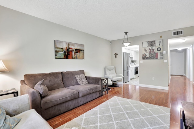 7451 NW 16th St Unit 303, Plantation, FL 33313 - living room with wood finished floors, visible vents, and a textured ceiling
