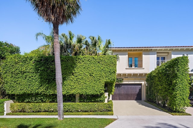 mediterranean / spanish-style house featuring stucco siding, a tile roof, concrete driveway, and an attached garage
