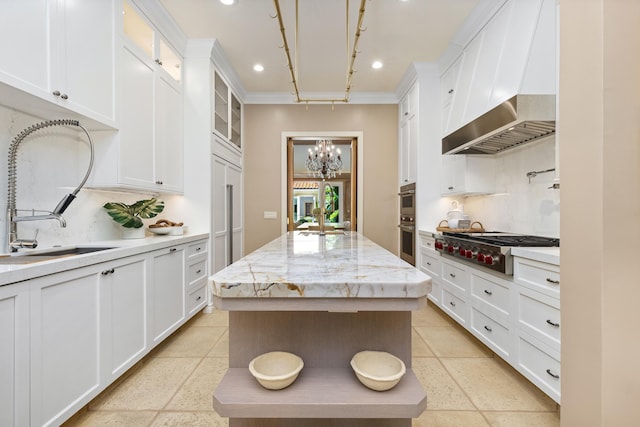 kitchen with wall chimney exhaust hood, an inviting chandelier, recessed lighting, a kitchen island, and appliances with stainless steel finishes