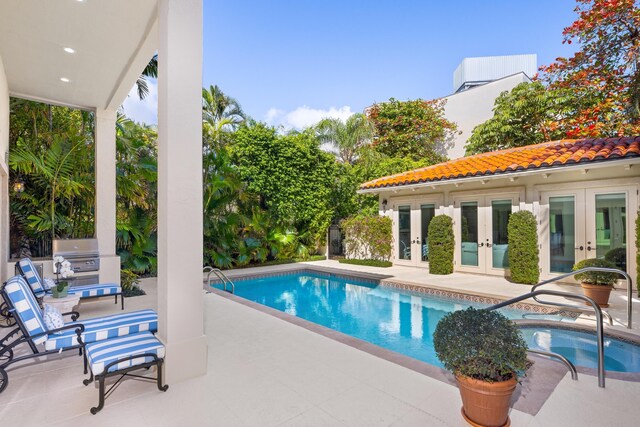 pool with grilling area, french doors, an in ground hot tub, and a patio