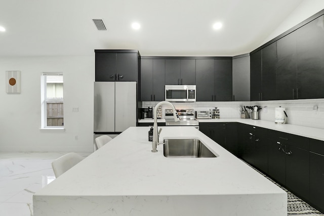 626 33rd St, West Palm Beach, FL 33407 - kitchen with stainless steel appliances, dark cabinetry, a sink, recessed lighting, and a kitchen island with sink