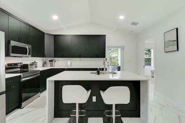 626 33rd St, West Palm Beach, FL 33407 - kitchen featuring dark cabinetry, appliances with stainless steel finishes, a sink, a kitchen bar, and vaulted ceiling