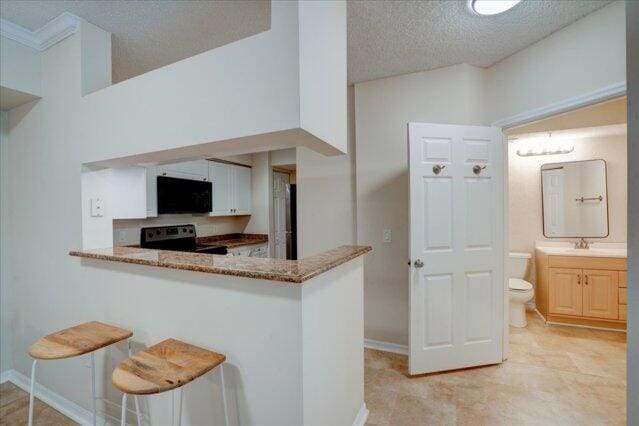 2221 Tuscany Way, Boynton Beach, FL 33435 - kitchen with light stone countertops, a peninsula, a textured ceiling, and appliances with stainless steel finishes