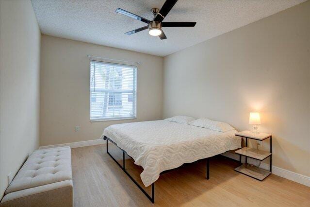 2221 Tuscany Way, Boynton Beach, FL 33435 - bedroom with light wood-type flooring, a ceiling fan, baseboards, and a textured ceiling