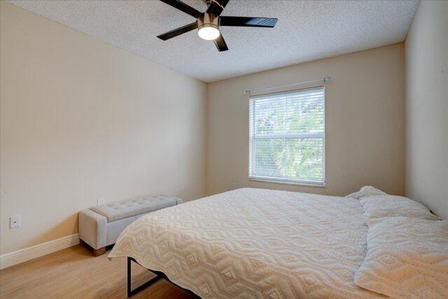 2221 Tuscany Way, Boynton Beach, FL 33435 - bedroom featuring light wood-style floors, a textured ceiling, a ceiling fan, and baseboards