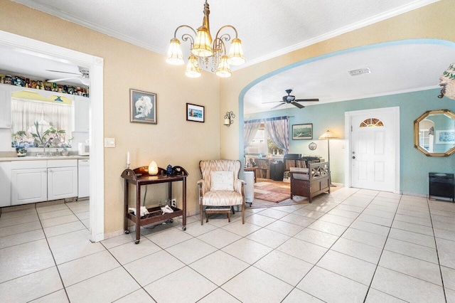 living area with arched walkways, ceiling fan with notable chandelier, ornamental molding, and light tile patterned flooring