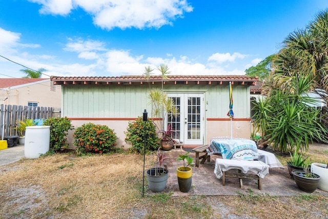 rear view of house featuring french doors, a patio area, fence, and a tiled roof