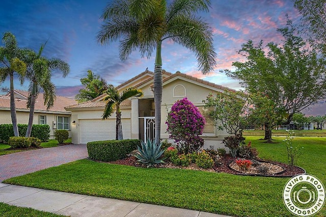 mid-century home with a garage, driveway, a tiled roof, a front yard, and stucco siding