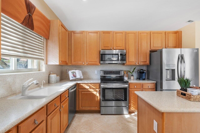 kitchen featuring light countertops, backsplash, a sink, light tile patterned flooring, and appliances with stainless steel finishes