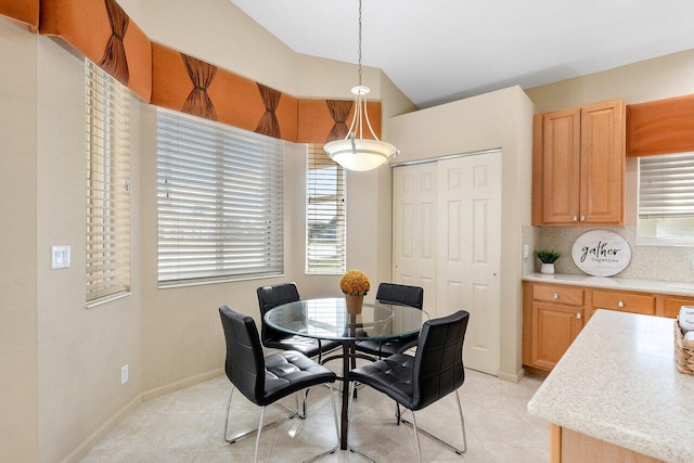 dining area with lofted ceiling, a wealth of natural light, baseboards, and light tile patterned floors