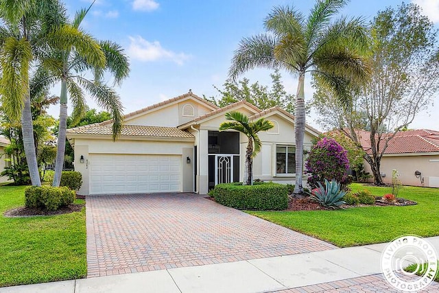 view of front of property with a tile roof, a garage, a front yard, stucco siding, and decorative driveway