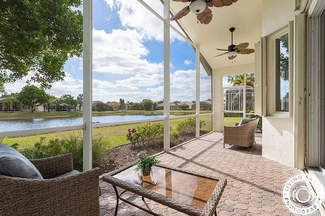 sunroom featuring a ceiling fan and a water view