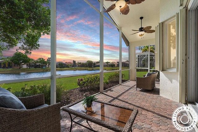 sunroom featuring a ceiling fan and a water view