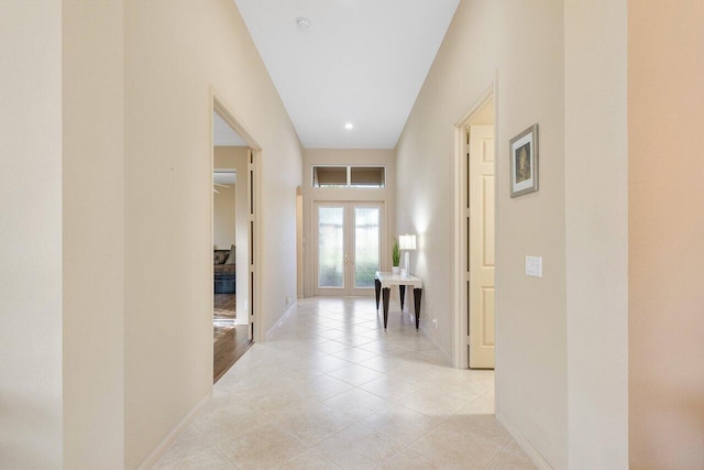 hallway featuring baseboards, french doors, and light tile patterned floors