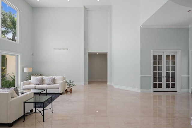 living area with a towering ceiling, french doors, marble finish floor, and baseboards