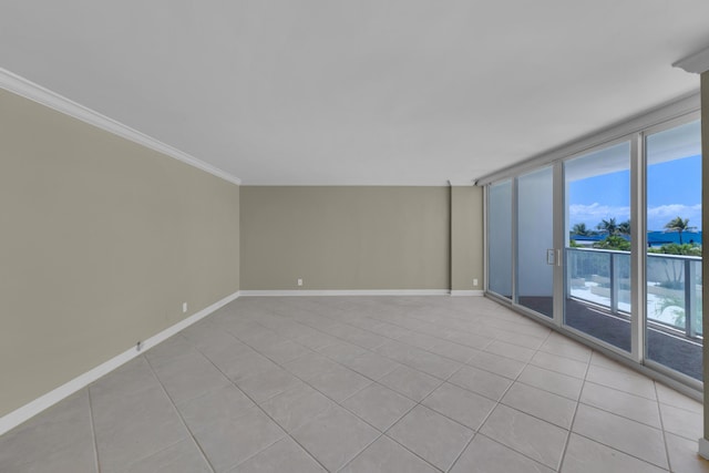 empty room featuring crown molding, light tile patterned flooring, and baseboards