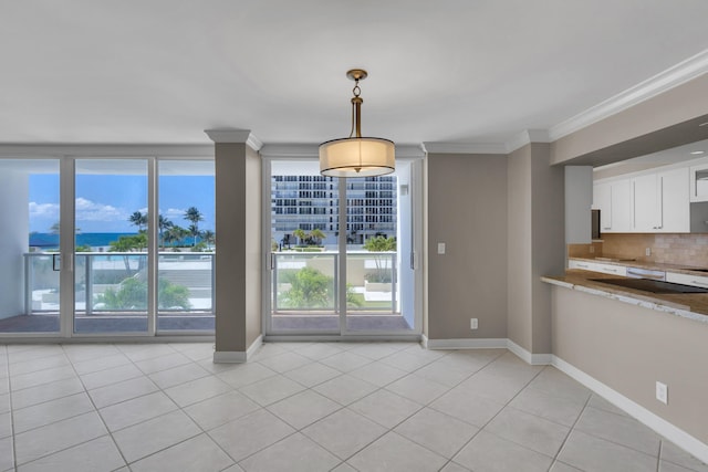unfurnished dining area featuring crown molding, baseboards, light tile patterned floors, and a water view