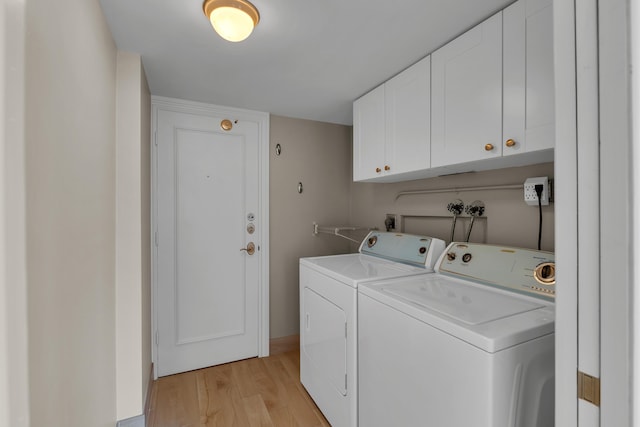 laundry area featuring washer and clothes dryer, cabinet space, light wood finished floors, and baseboards