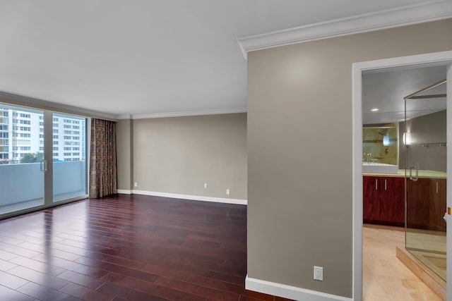unfurnished room featuring ornamental molding, baseboards, and wood finished floors