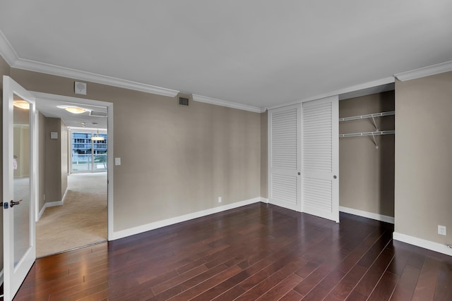 unfurnished bedroom featuring baseboards, wood finished floors, ornamental molding, and a closet