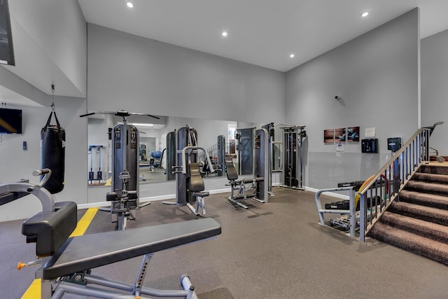 gym featuring a towering ceiling, recessed lighting, and baseboards