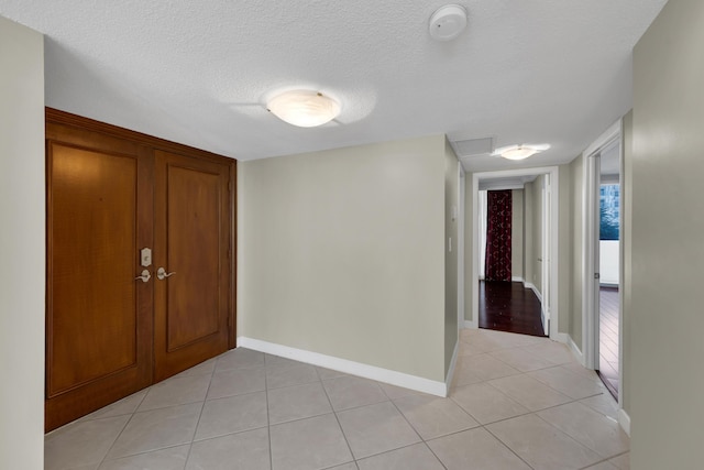 entrance foyer with light tile patterned floors, baseboards, and a textured ceiling