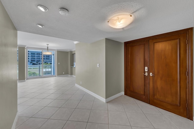 entryway featuring light tile patterned flooring, baseboards, and a textured ceiling
