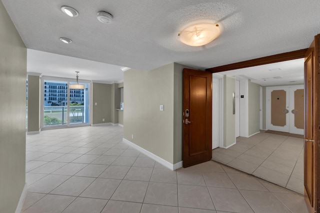 unfurnished room featuring light tile patterned floors, a textured ceiling, and baseboards