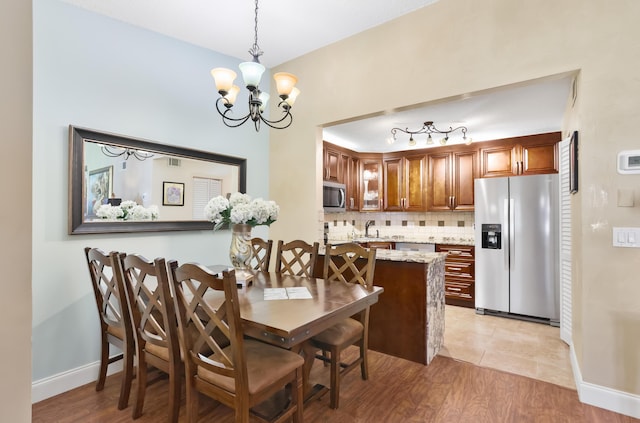 dining area featuring visible vents, a notable chandelier, light wood-style flooring, and baseboards
