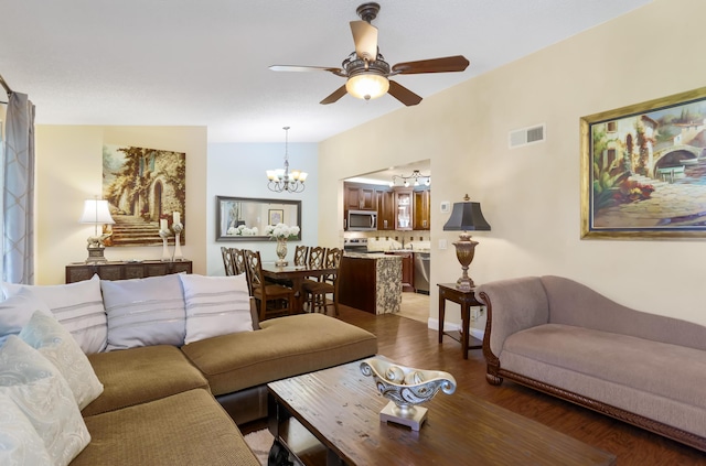 living area with wood finished floors, visible vents, and ceiling fan with notable chandelier