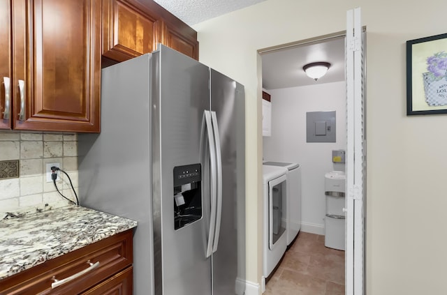 kitchen with light stone countertops, decorative backsplash, electric panel, washer and dryer, and stainless steel fridge with ice dispenser