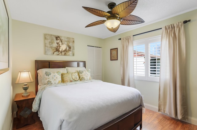 bedroom with wood finished floors, a ceiling fan, baseboards, and a closet