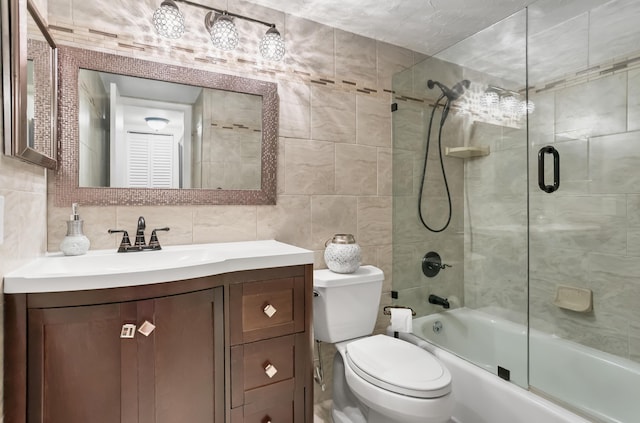full bathroom with tile walls, bath / shower combo with glass door, vanity, and decorative backsplash