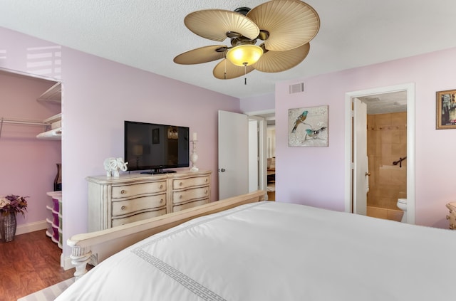 bedroom with connected bathroom, a closet, visible vents, a walk in closet, and wood finished floors
