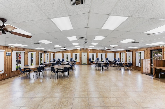 miscellaneous room featuring visible vents, a ceiling fan, wooden walls, and a drop ceiling