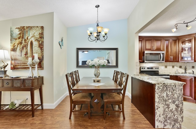 dining room with light wood finished floors, an inviting chandelier, and baseboards