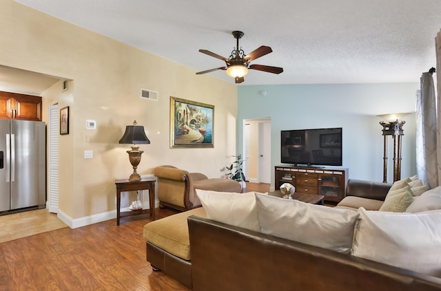 living room with baseboards, visible vents, ceiling fan, and light wood-style flooring