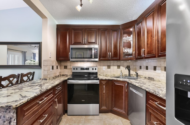 kitchen featuring backsplash, a textured ceiling, a sink, and appliances with stainless steel finishes