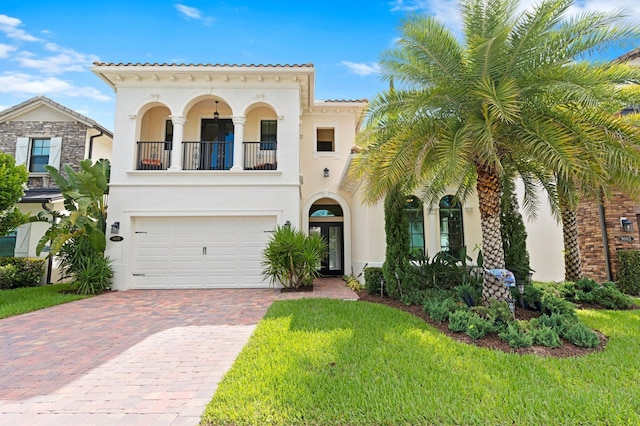 mediterranean / spanish-style home featuring decorative driveway, a balcony, a tiled roof, a garage, and stucco siding