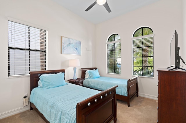 bedroom featuring ceiling fan, baseboards, and light colored carpet