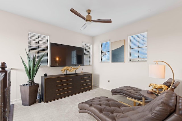 living area featuring baseboards, light colored carpet, and ceiling fan