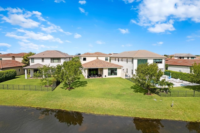 rear view of property with a residential view, a lawn, a fenced backyard, and a water view