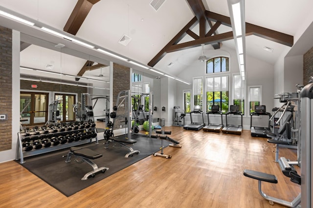gym featuring baseboards, wood finished floors, visible vents, and high vaulted ceiling