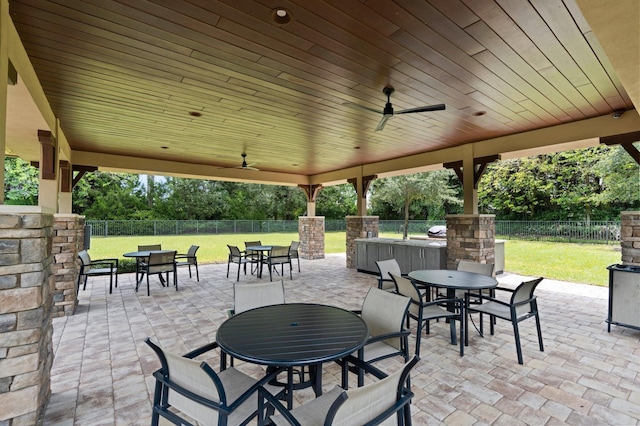 view of patio / terrace with a fenced backyard, an outdoor stone fireplace, outdoor dining space, and ceiling fan