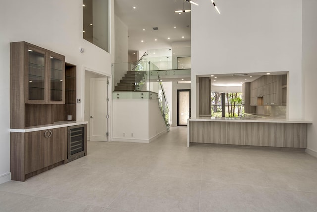 13890 Parc Dr, Palm Beach Gardens, FL 33410 - unfurnished living room with a towering ceiling, wine cooler, stairway, baseboards, and recessed lighting