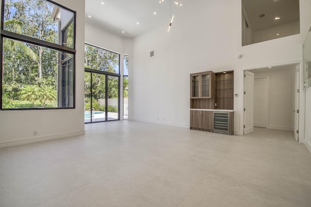 13890 Parc Dr, Palm Beach Gardens, FL 33410 - unfurnished living room with a high ceiling, baseboards, recessed lighting, and finished concrete flooring