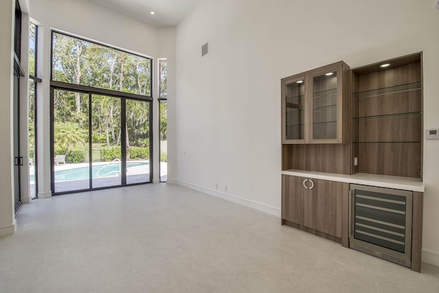 13890 Parc Dr, Palm Beach Gardens, FL 33410 - unfurnished living room with wine cooler, baseboards, a high ceiling, and recessed lighting